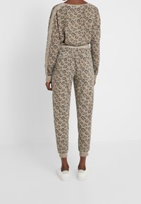 Beiger und grauer Loungewear-Set mit Leopardenmuster, bestehend aus einem lässig geschnittenen Oberteil und einer Hose mit gerippten Bündchen und weicher Textur.