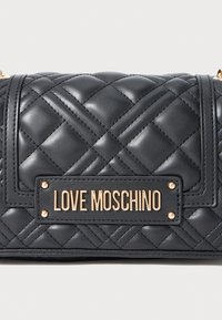 Crna torba od quilted kože s zlatnom oznakom "LOVE MOSCHINO" na prednjoj strani i zlatnim spojnicama za lanac.