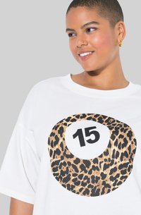Hvid oversized t-shirt med et leopardprint cirkel og tallet "15" i sort. Blødt bomuldsstof; afslappet pasform.