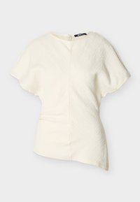 Ασύμμετρο κοντομάνικο μπλουζάκι σε εκρού χρώμα με υφή υφάσματος και κλείσιμο με φερμουάρ στο πλάι.