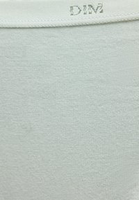 Ανοιχτό γκρι ύφασμα με ορατή πλεκτή υφή και ραμμένη λευκή ταινία στο πάνω μέρος με μερικώς ορατό γκρι κεντημένο κείμενο "DIM".