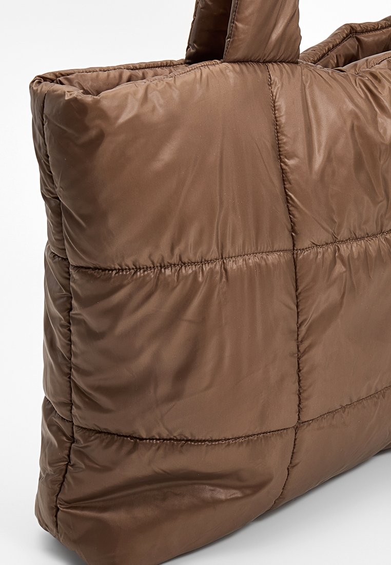 Braune gesteppte Tragetasche aus glänzendem Nylonstoff, mit gepolstertem Design, zwei kurzen Griffen und sichtbaren Steppnähten.