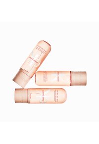 Trois bouteilles de parfum CK Sheer Peach en plastique translucide pêche, avec des étiquettes blanches et argentées. Chaque bouteille a un capuchon arrondi.
