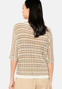 Leichtes, offen gestricktes Sweater in creme und beigen Streifen. Verfügt über kurze Ärmel, eine lockere Passform und einen gerippten Saum. Strukturiertes Design im gesamten Spiel.
