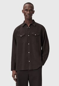 Μαύρο πουκάμισο με μακριά μανίκια, δύο τσέπες στο στήθος, μυτερό γιακά και κλείσιμο με κουμπιά μπροστά. Λεία υφή με άνετη εφαρμογή.