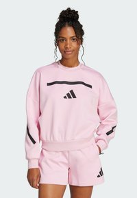 Pink sweatshirt with black stripes and Adidas logo, featuring a round neckline and ribbed cuffs, paired with matching pink shorts.