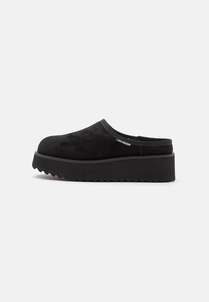 Chaussure plateforme noire slip-on avec semelle épaisse crantée et dessus souple, avec une petite étiquette "I Love Moschino" sur le côté.