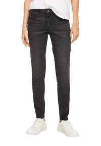 Zwarte skinny jeans van denim, met een vijf-pocket ontwerp, riemlussen en een subtiele vervaagde textuur, gecombineerd met witte sneakers.