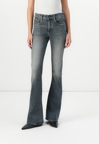 Jeans bootcut in denim grigio sbiadito, con un classico design a cinque tasche e una leggera svasatura all'orlo, abbinati a scarpe nere a punta.