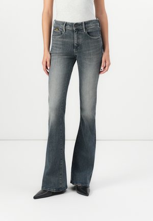 Bootcut jeans in faded gray denim, featuring a classic five-pocket design and a slight flare at the hem, paired with pointed black shoes.