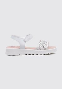 Sandalias blancas con un diseño superior perforado, correa ajustable y suela de goma gruesa. Plantilla de color rosa claro y suela texturizada para agarre.