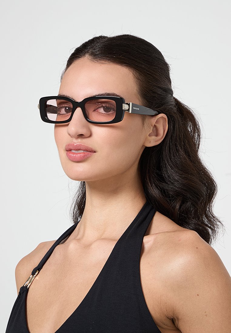 Gafas de sol negras de forma rectangular con un marco grueso, lentes tintados y acentos plateados. Las varillas presentan detalles sutiles de marca.
