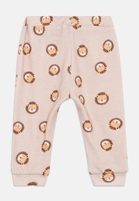 Lyse rosa barnebukser laget av mykt stoff, med et gjentatt løveutskrift i brunt og beige foran og bak.