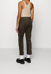 Khaki corduroy broek met een tapered fit, met achterzakken en gecombineerd met zwarte stevige schoenen en witte sokken.