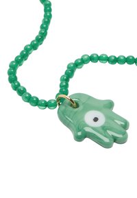 Zielona naszyjnik z koralików z przezroczystym zielonym wisiorkiem w kształcie dłoni z białym detalem oka i małym złotym zapięciem.