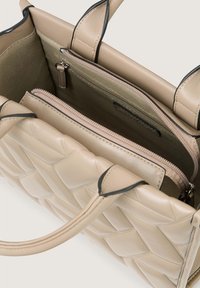 Sac à main en cuir beige avec une texture tissée. Dispose de deux poignées supérieures, d'une poche intérieure zippée et d'un intérieur lisse.