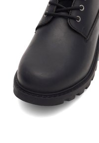 Čierne kožené topánky s okrúhlou špičkou, kovovými očkami a robustnou podošvou s hlbokými trakčnými vzormi. Hladká textúra.