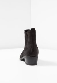 Czarne zamszowe botki za kostkę z niskim obcasem, z elastycznymi bocznymi panelami i pętlą z tyłu ułatwiającą zakładanie. Gładka tekstura.
