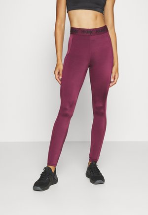 Leggings bourgogne avec une taille élastique noire portant le logo "HKMX". Fabriqués en tissu extensible, conçus pour le confort et le mouvement.