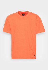T-shirt a maniche corte di un vivace arancione, realizzato in cotone morbido. Presenta un collo rotondo e un piccolo etichetta del logo sul lato sinistro in basso.