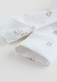 Tissu en coton avec un fond blanc orné d'impressions d'animaux pastel clairs, comprenant des moutons et des ours, avec des manches retroussées et une texture douce.