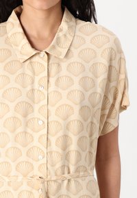 Beige skjortekjole med skjellmønster, med klassisk krage, korte ermer, knappestolpe og beltedetalj i midjen.