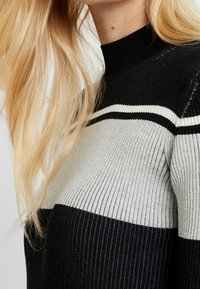 Maglione a righe nero e grigio, con collo alto, caratterizzato da ampie righe orizzontali e tessuto texture.