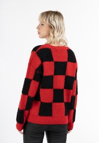 Rood en zwart geblokt gebreid sweater met een fuzzy textuur, ribbelboorden en zoom, met grote afwisselende vierkanten in een losvallend ontwerp.