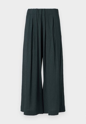 Donkergroene brede broekspijpen van een gestructureerde stof, met een hoge elastische tailleband en voorplooien, eindigend boven de enkels.