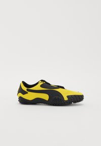 Yellow and black athletic shoe with a textured surface, curved design, and spiked outsole for traction. Elastic laces and rounded toe.