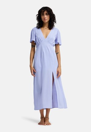 Robe maxi violet clair avec manches courtes évasées, un décolleté profond en V et une fente latérale. Confectionnée dans un tissu texturé pour une coupe décontractée.