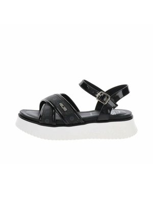 Sandale noire à bout ouvert avec bride de cheville réglable, brides avant croisées avec logos et semelle blanche épaisse pour un usage décontracté.