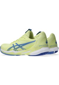 Baskets de sport jaune vif avec des accents bleus, tige en mesh et semelle blanche. Les caractéristiques incluent un col rembourré et une semelle extérieure à grip texturé.