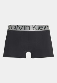 Crne bokserice od mekanog, rastezljivog materijala. Imaju sivi pojas s natpisom "Calvin Klein" ispisanim crnim slovima.