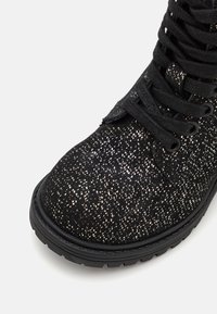 Černé kotníkové boty s texturovaným povrchem a metalickými kapičkami, kulatou špičkou a černými tkaničkami. Gumová podrážka s dezénem.