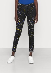 Jeans negros con un patrón de salpicaduras de pintura en amarillo, azul y blanco. Corte slim con un diseño clásico de cinco bolsillos y cremallera.