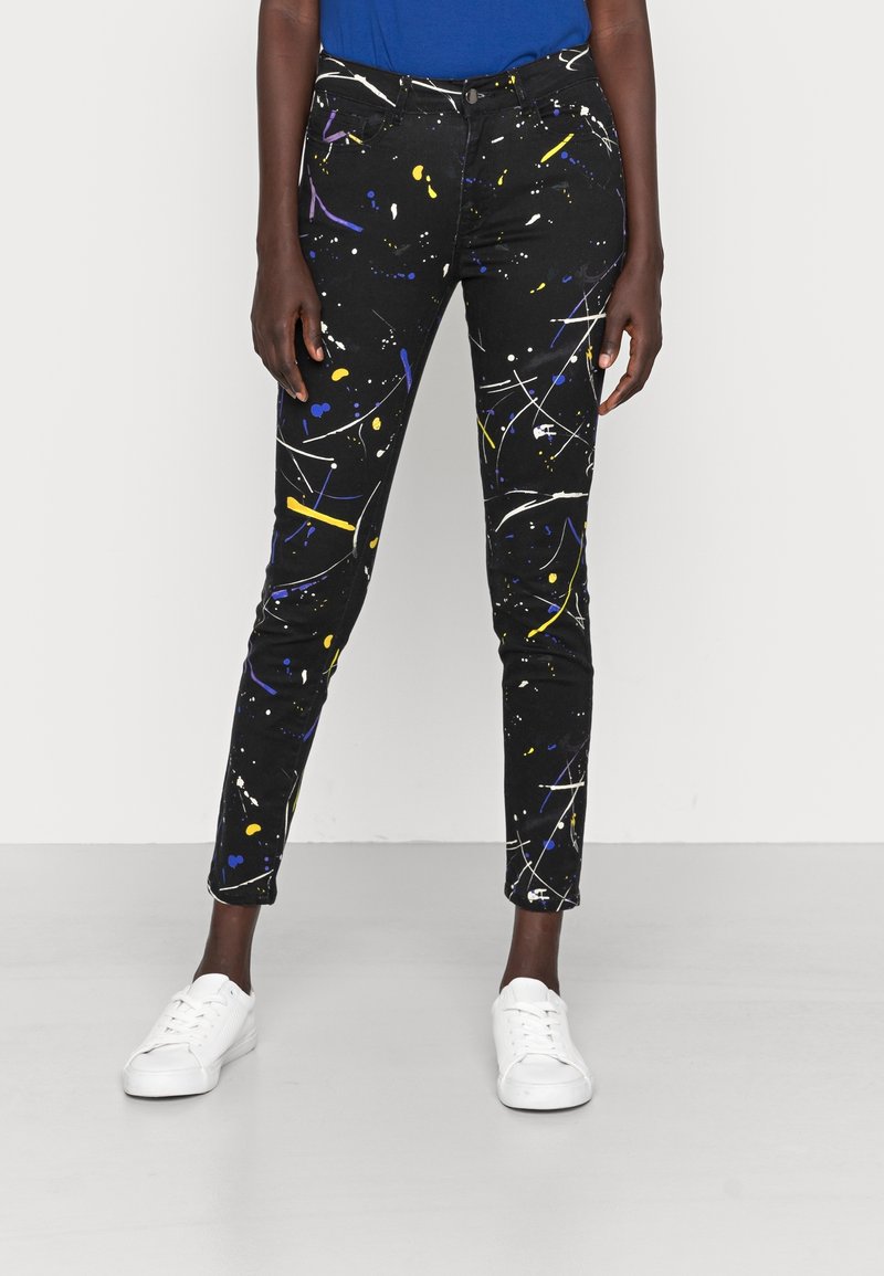 Jeans negros con un patrón de salpicaduras de pintura en amarillo, azul y blanco. Corte slim con un diseño clásico de cinco bolsillos y cremallera.