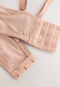 Svjetloružičasti grudnjak sa podesivim naramenicama, glatkim tkanjem, kopčanjem na kukicu i petlju te ojačanim šavovima. Ima meku mrežastu teksturu i elastične detalje.