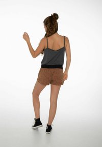 Top grigio senza maniche con spalline sottili, abbinato a pantaloni corti maculati marroni con vita elastica nera. Scarpe nere alte completano l'outfit.