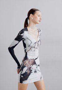Long-sleeve dress featuring a marble-patterned body with a plunging neckline, fitted silhouette, and contrasting black sleeves.
