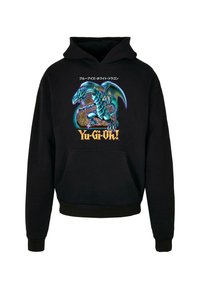 Sudadera negra con un gráfico vibrante de un dragón azul y el texto "Yu-Gi-Oh!". El material parece suave y cuenta con un bolsillo tipo canguro en la parte frontal.
