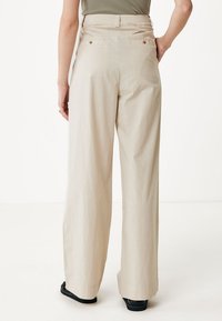 Beige weite Hose aus leichtem Stoff, mit hoher Taille, zwei Gesäßtaschen und dezenten Nähdetails.