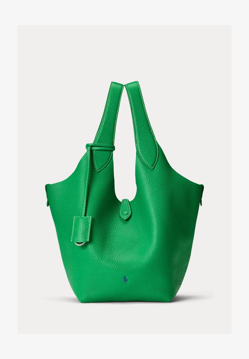 Spilgti zaļas faktūras ādas soma ar platām rokturiem, nelielu aizdari ar cilpiņu un smalku tumši zilu izšūtu logotipu netālu no pamatnes.