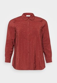 Chemise rouge à manches longues en tissu léger et lisse, dotée d'un col à boutons, de deux poches avant et d'ornements en pointillés argentés.