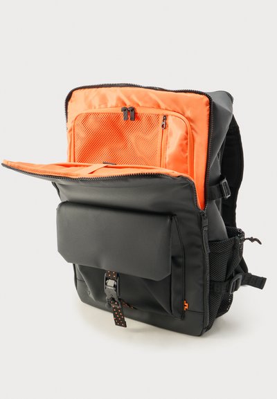 Μαύρο σακίδιο με φωτεινή πορτοκαλί εσωτερική επένδυση, η μπροστινή τσέπη έχει ανοιχτεί πλήρως και αποκαλύπτει θήκες με φερμουάρ από δίχτυ και οργανωτικές θέσεις.