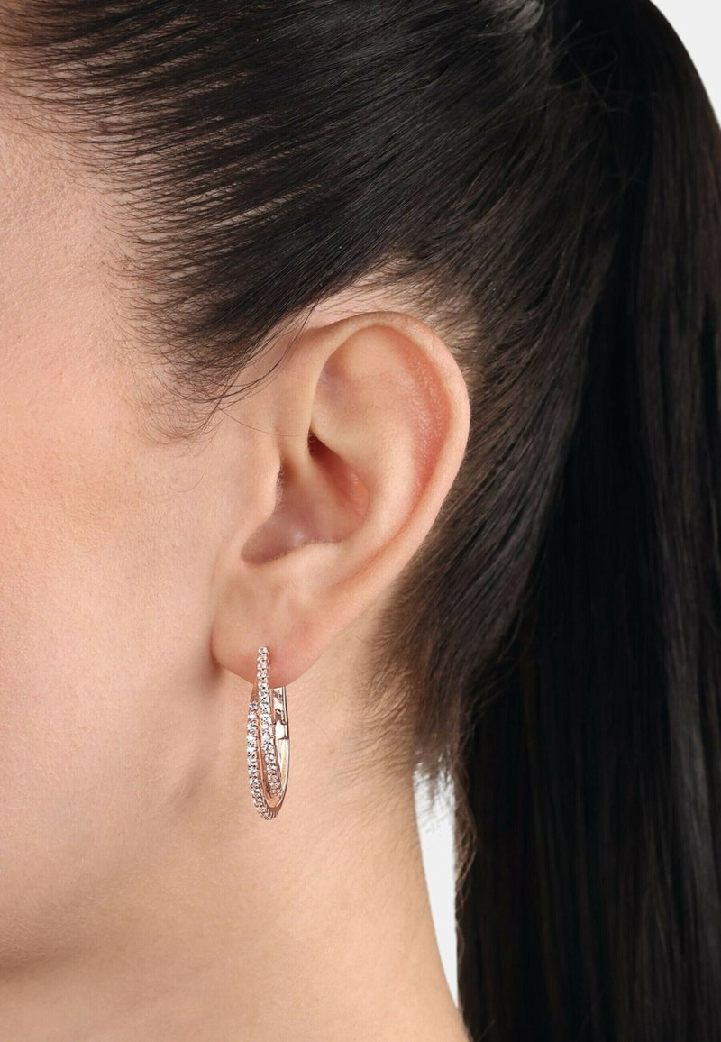 Orecchini a cerchio in oro rosa con design intrecciato, dotati di accenti in zirconia cubica trasparente lungo un bordo, che evidenziano una finitura lucida.