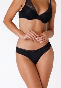 Seno con pizzi neri, realizzato con un design a coste e completi di bikini neri abbinati. Presenta delicati dettagli in pizzo sulle coppe del reggiseno e sulla vita.