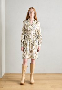Rochie cu imprimeu floral în bej, cu nuanțe de verde și albastru, având talie cu curea, mâneci lungi și guler. Suprapusă cu botine bej până la genunchi.