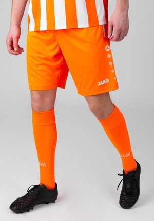 Helle orange Fußballshorts mit passenden knielangen Socken. Merkmale sind das Logo und Akzente im kreisförmigen Muster, gefertigt aus leichtem Material.