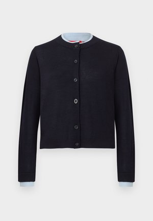 Mornarsko modra skrajšana jopica iz lahkega pletenega blaga. Ima okroglo ovratnico, gumbno zapiranje in kontrastne svetlo modre manšete.